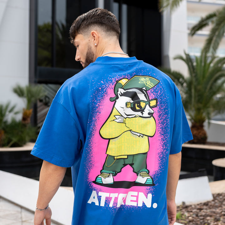 Person wearing a blue t-shirt with a colorful graphic design outdoors.