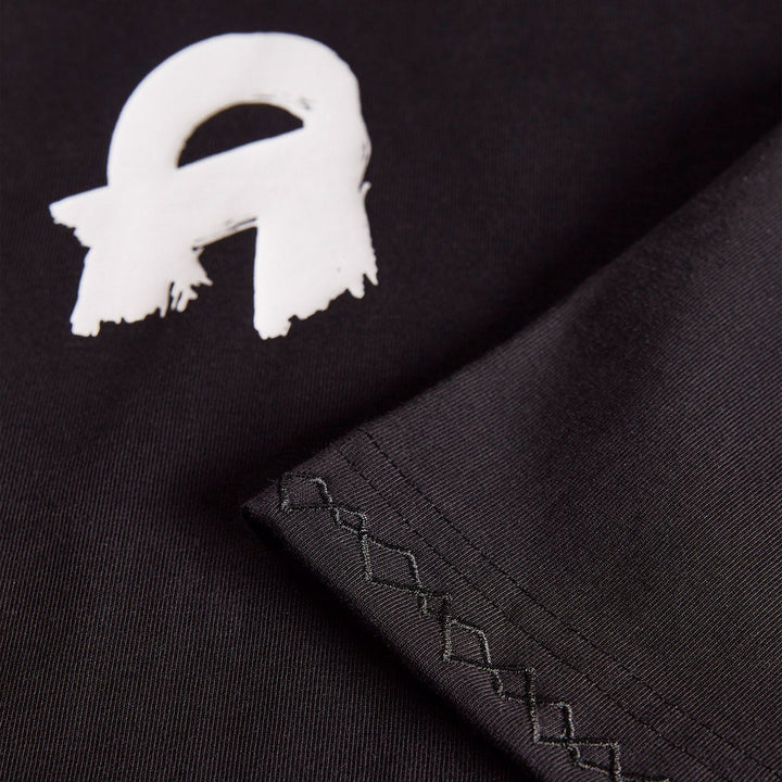 Close-up of a black garment with white fringe detail and stitching.